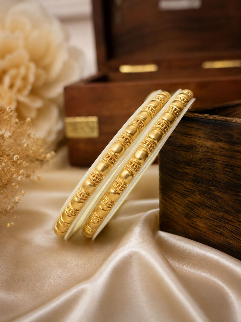 Gold bangles on a satin surface with a wooden box in the background